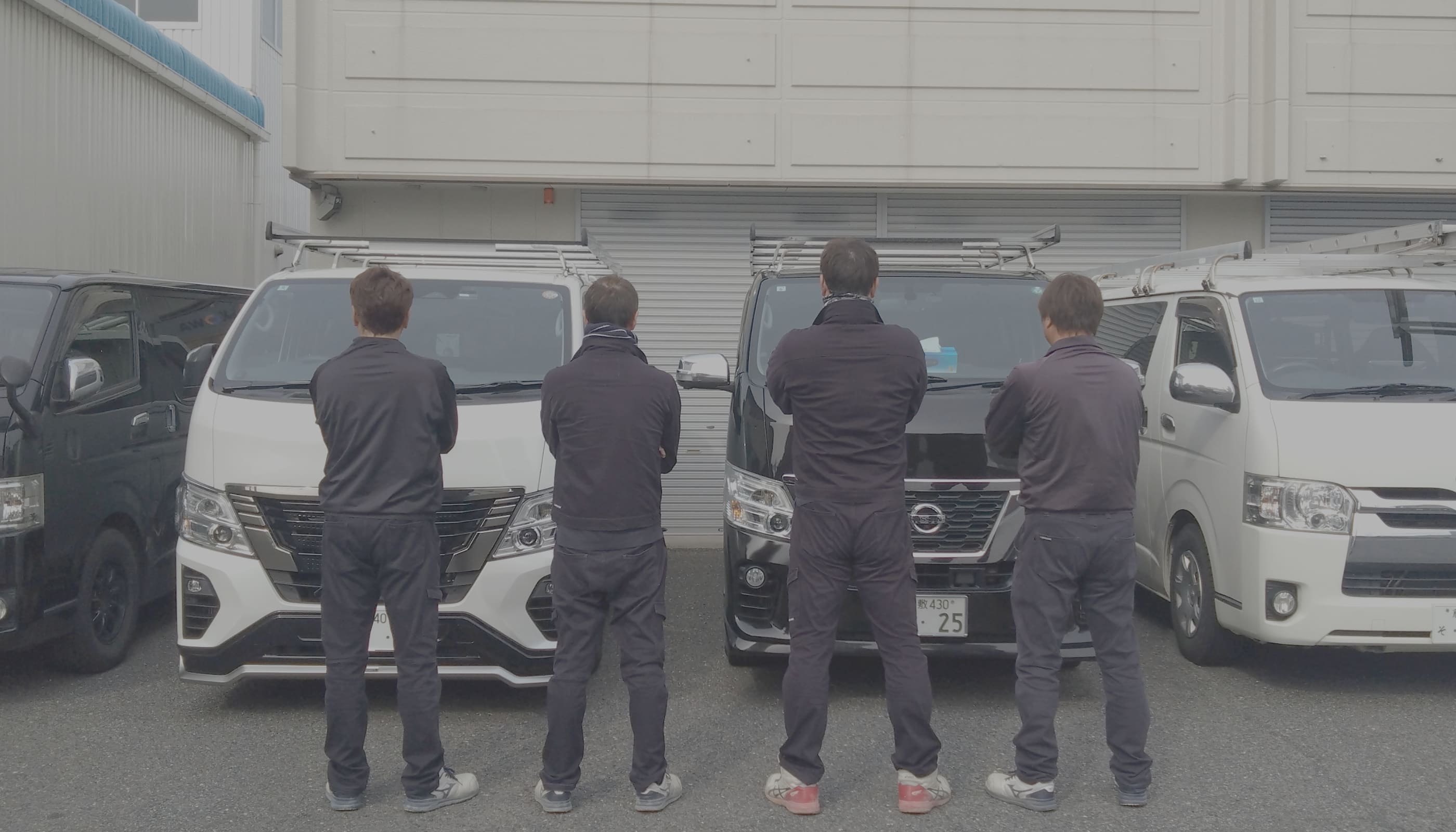 会社の前に立つ4人の男性の写真